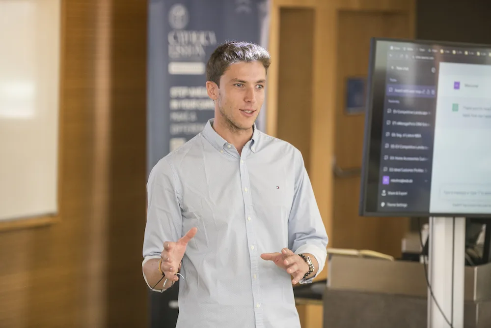 Marco Kohns teaching a seminar at Católica-Lisbon, an AI application on the screen behind him